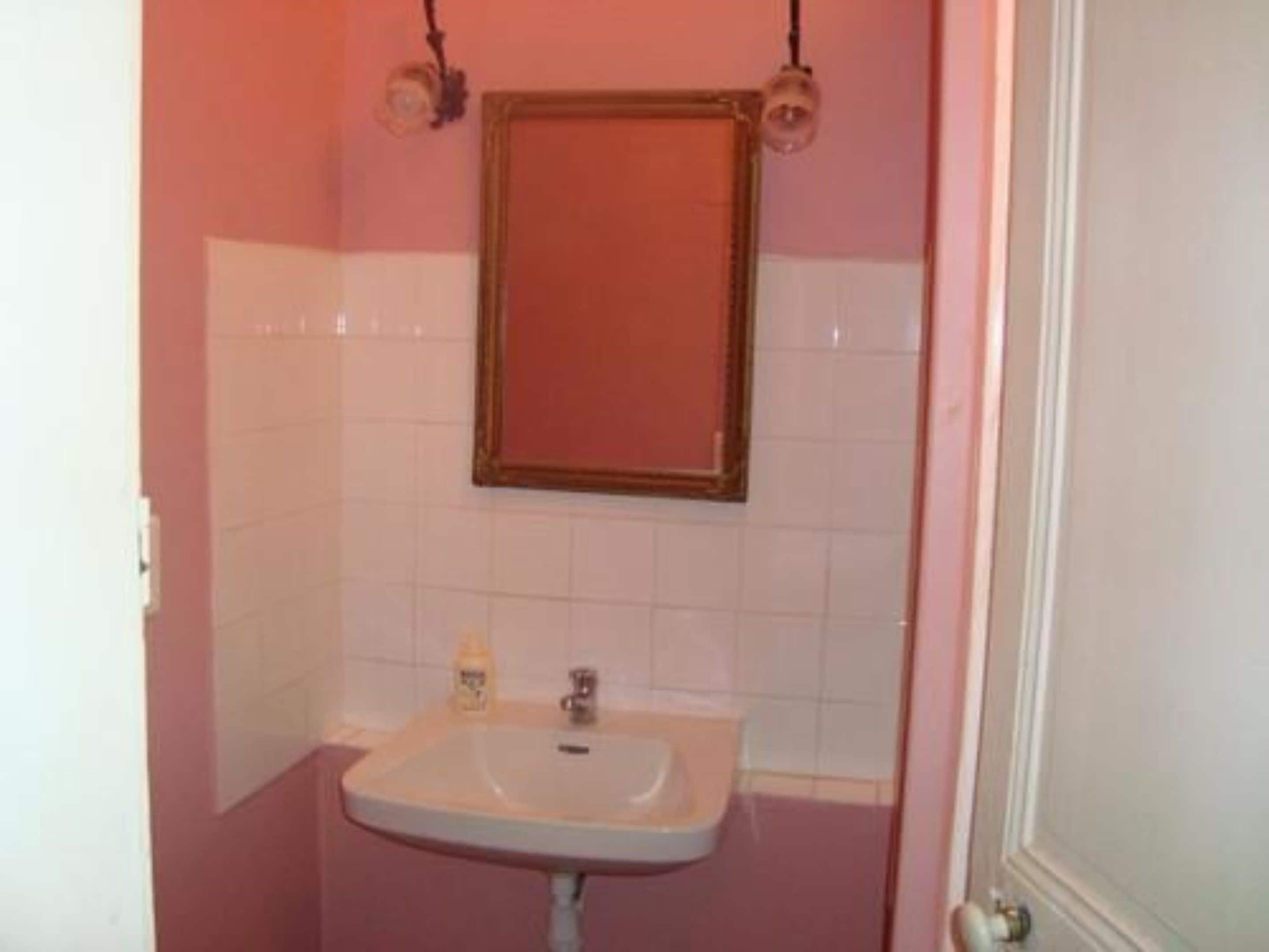 Un baño con lavamanos blanco, espejo y retrete.