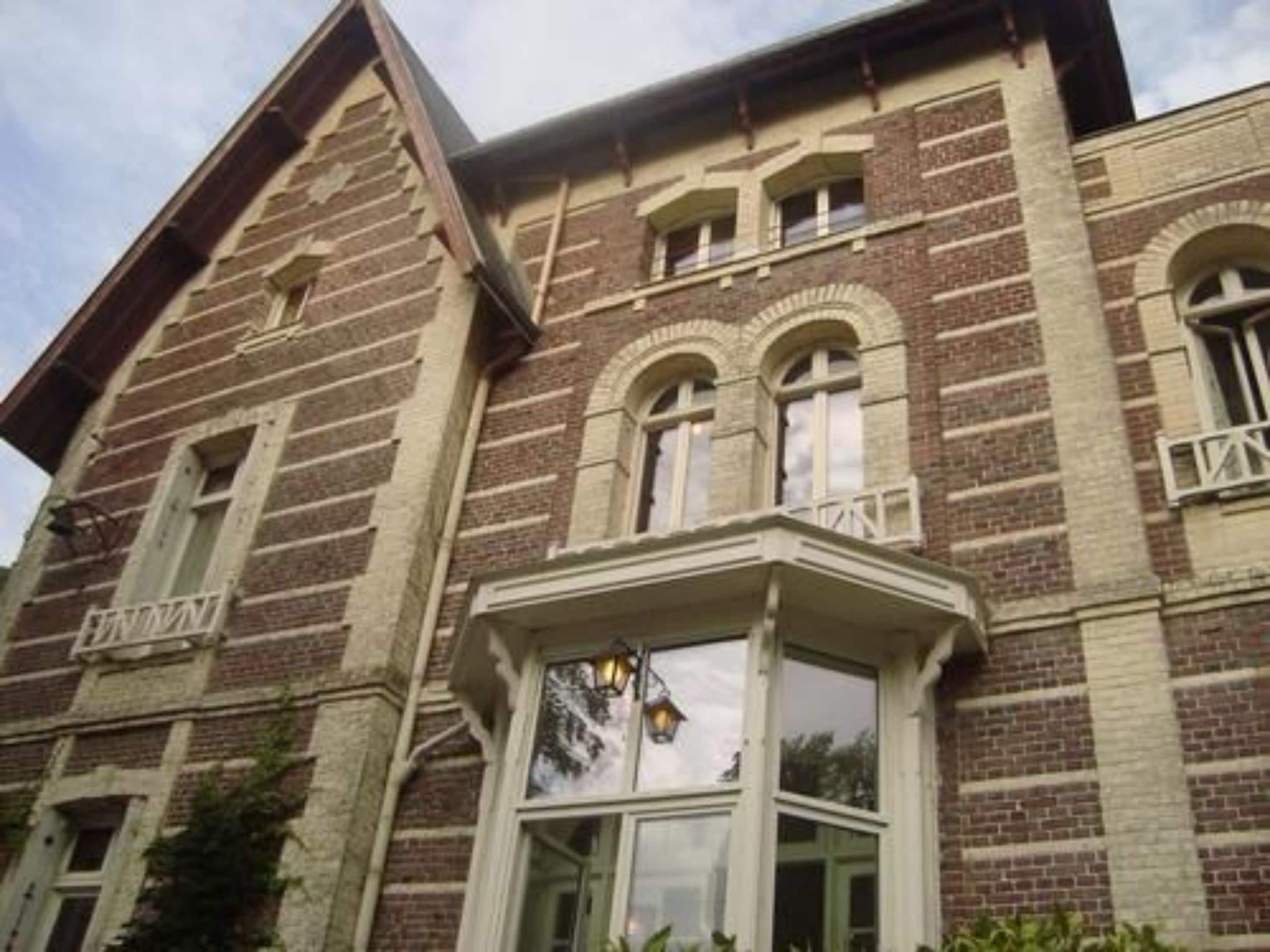 A brick building with a bay window and multiple windows.