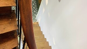Een houten wenteltrap met een metalen leuning en witte wanden.