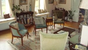 Een gezellige woonkamer met een open haard, comfortabele zitplaatsen en kunstwerken aan de muur.
