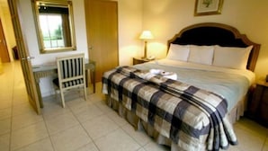 A neatly arranged bedroom with a bed, bedside table, lamp, and a chair. - Avalon Grand Panama (Panama City)