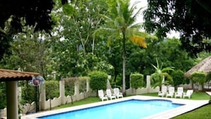 A rectangular swimming pool with a white border, surrounded by a low hedge and white lounge chairs. - Avalon Grand Panama (Panama City)
