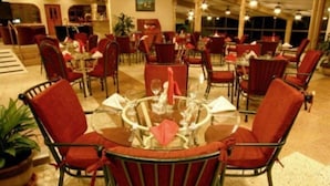 A spacious indoor dining area with multiple tables and chairs, featuring a classic design with red upholstered chairs and a central glass table. - Avalon Grand Panama (Panama City)