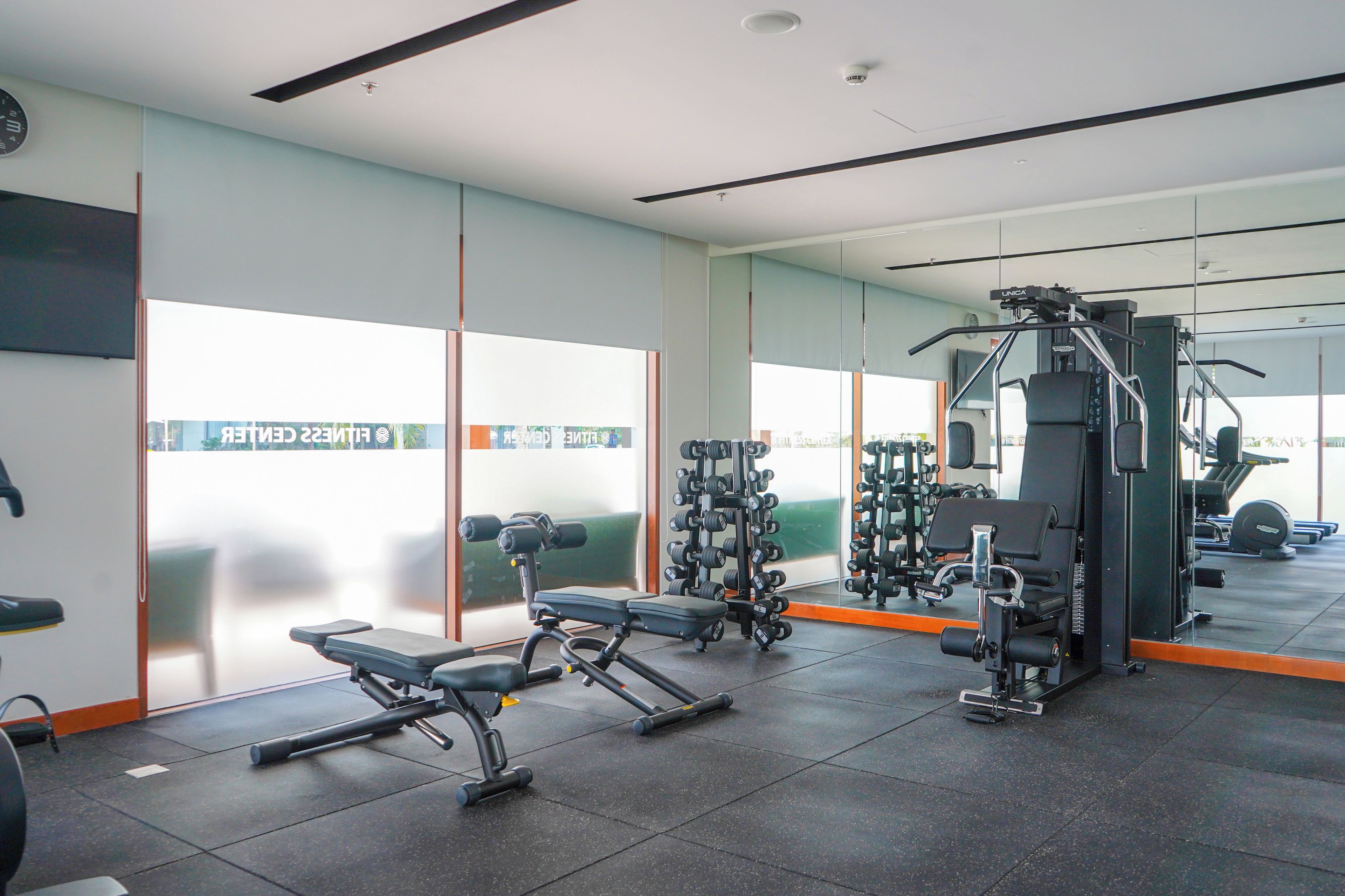 A gym with exercise equipment, large windows, and a mirror wall.