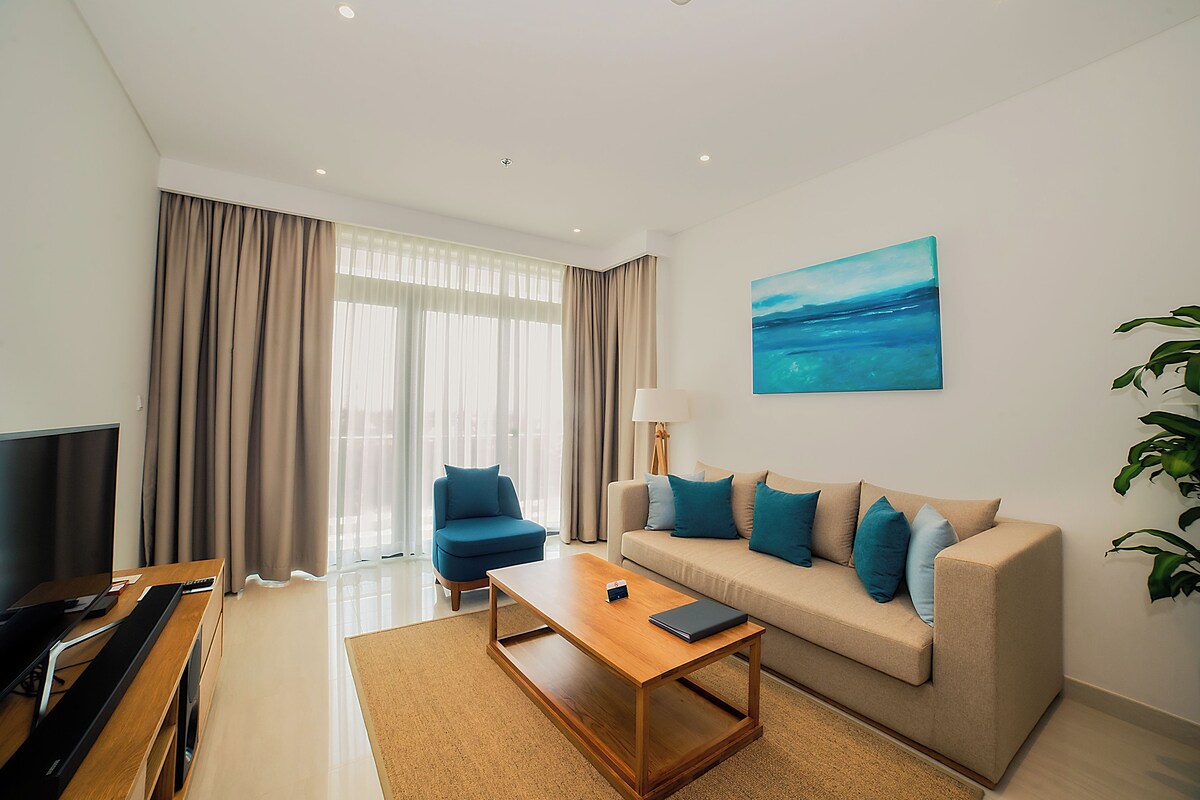 A modern living room with a TV, sofa, coffee table, and a painting on the wall.