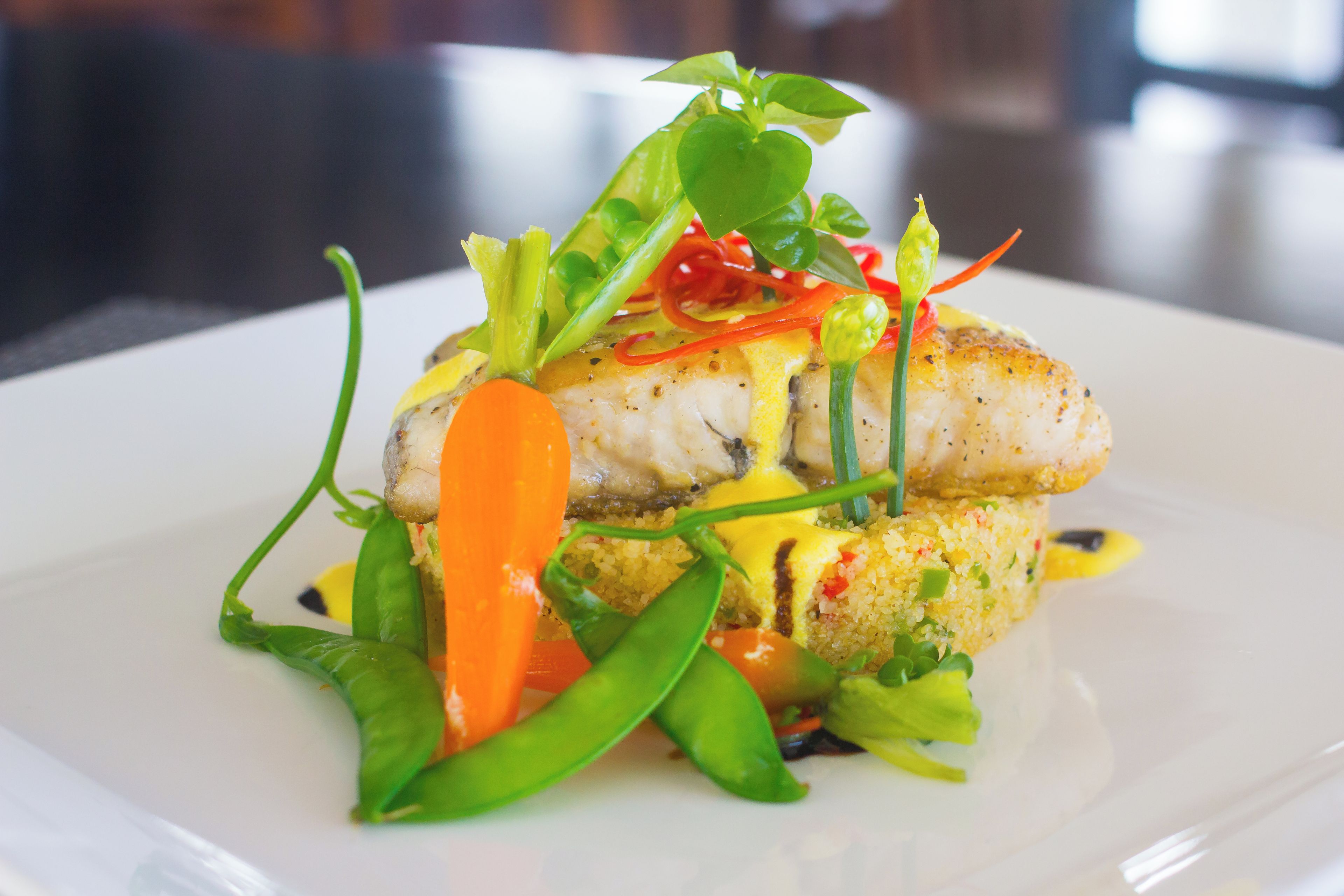 Un plato con pescado, verduras y salsa.