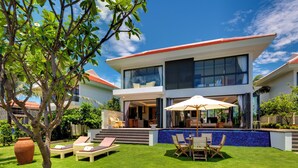 A modern two-story house with a swimming pool, outdoor seating area, and lush greenery. - The Ocean Villas (Da Nang)