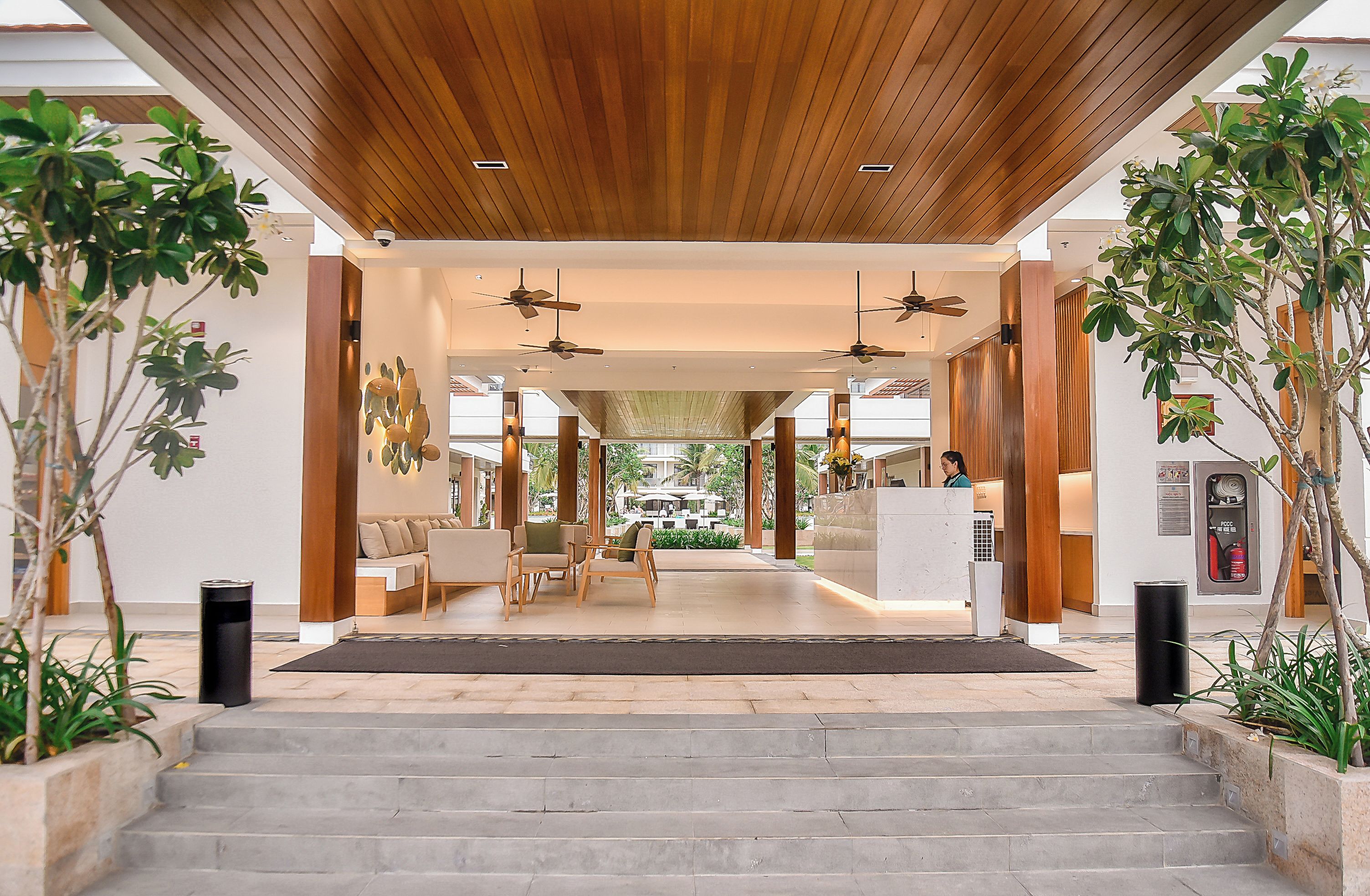 A hotel lobby with a wooden ceiling, a reception desk, and seating area.