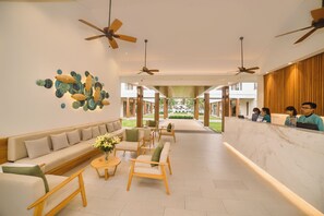 A hotel lobby with a reception desk, seating area, and ceiling fans. - The Ocean Villas (Da Nang Municipality)