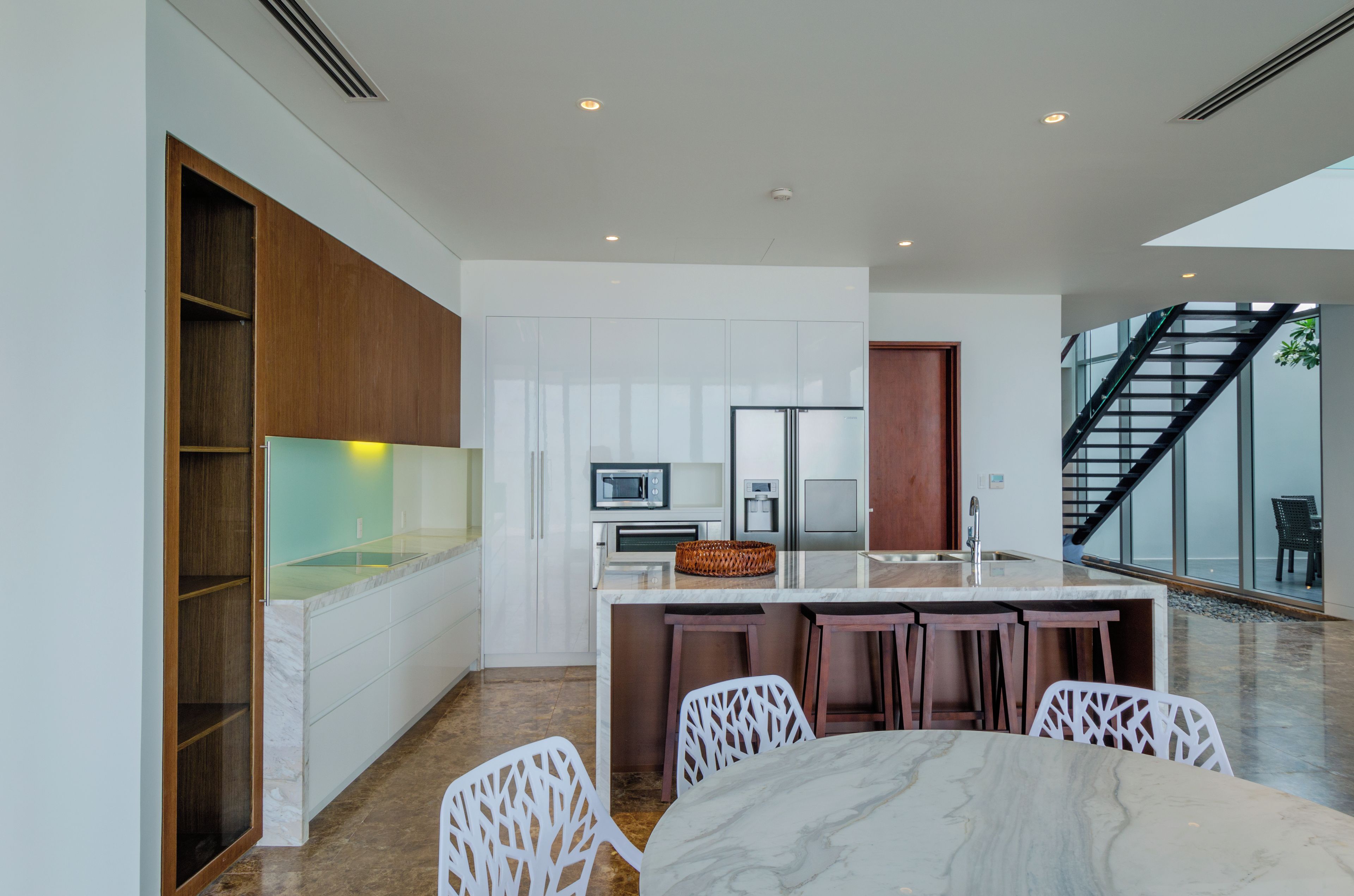 A modern kitchen with white cabinetry, a marble countertop, and a built-in oven.