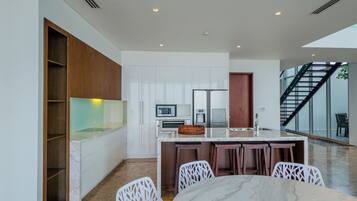 A modern kitchen with white cabinetry, a marble countertop, and a built-in oven.