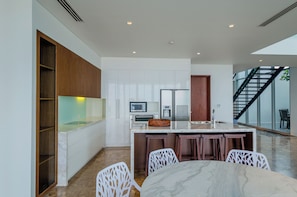 A modern kitchen with white cabinetry, a marble countertop, and a built-in oven. - The Ocean Villas (Da Nang Municipality)