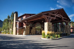 A lodge with a stone facade, a covered entrance, and a mountain backdrop. - Wyoming Inn of Jackson Hole (Jackson)