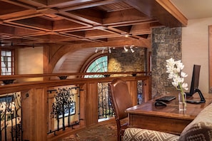 A wooden interior with a stone fireplace, a desk with a computer, and a chair. - Wyoming Inn of Jackson Hole (Jackson)