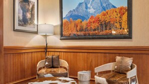 A room with two chairs upholstered in faux fur, a wooden bench, and a framed picture of a mountain landscape. - Wyoming Inn of Jackson Hole (Jackson)