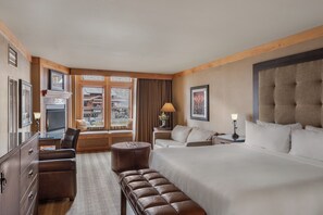 A hotel room with a large bed, a desk with a chair, a sofa, a small round ottoman, a television, and a window with curtains. - Wyoming Inn of Jackson Hole (Jackson)