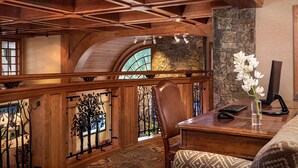A wooden interior with a stone fireplace, a desk with a computer, and a chair. - Wyoming Inn of Jackson Hole (Jackson)