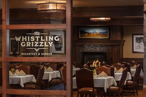 A restaurant interior with wooden decor, tables set for dining, and a fireplace. - Wyoming Inn of Jackson Hole (Jackson)