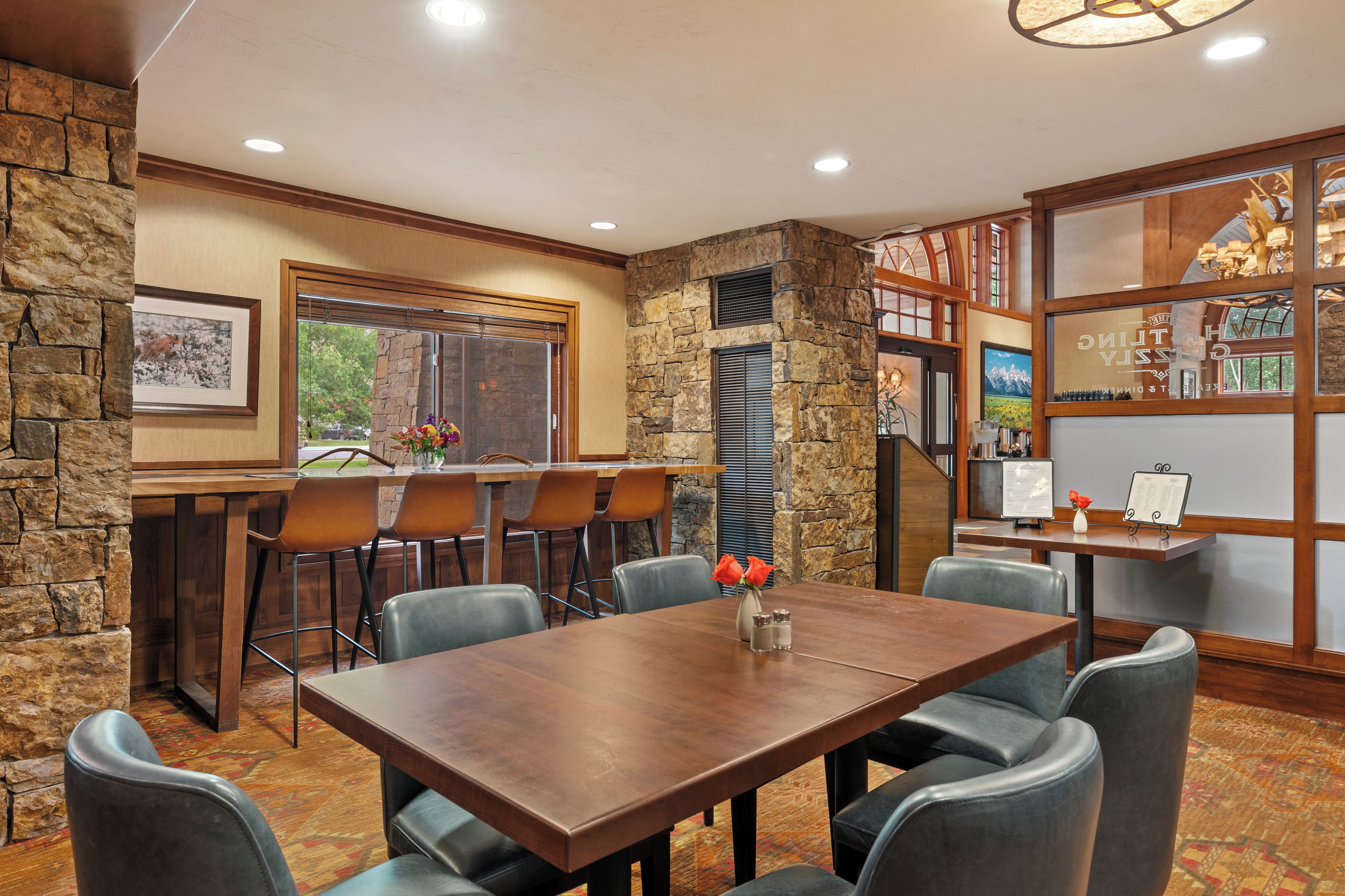 A dining area with a stone accent wall, a wooden table, and several chairs.