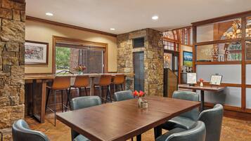 A dining area with a stone accent wall, a wooden table, and several chairs.