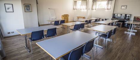 A classroom with wooden desks and chairs, a whiteboard, and a projector screen.
