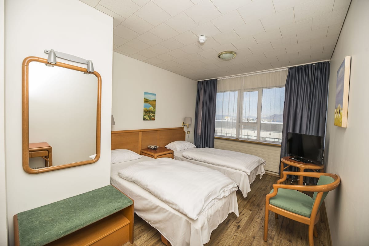 Ein Hotelzimmer mit zwei Betten, einem Fernseher, einem kleinen Tisch und einem Stuhl.