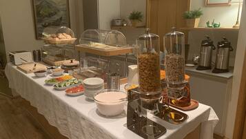 A buffet setup with various food items and beverages, including cereal, fruits, and a coffee station.