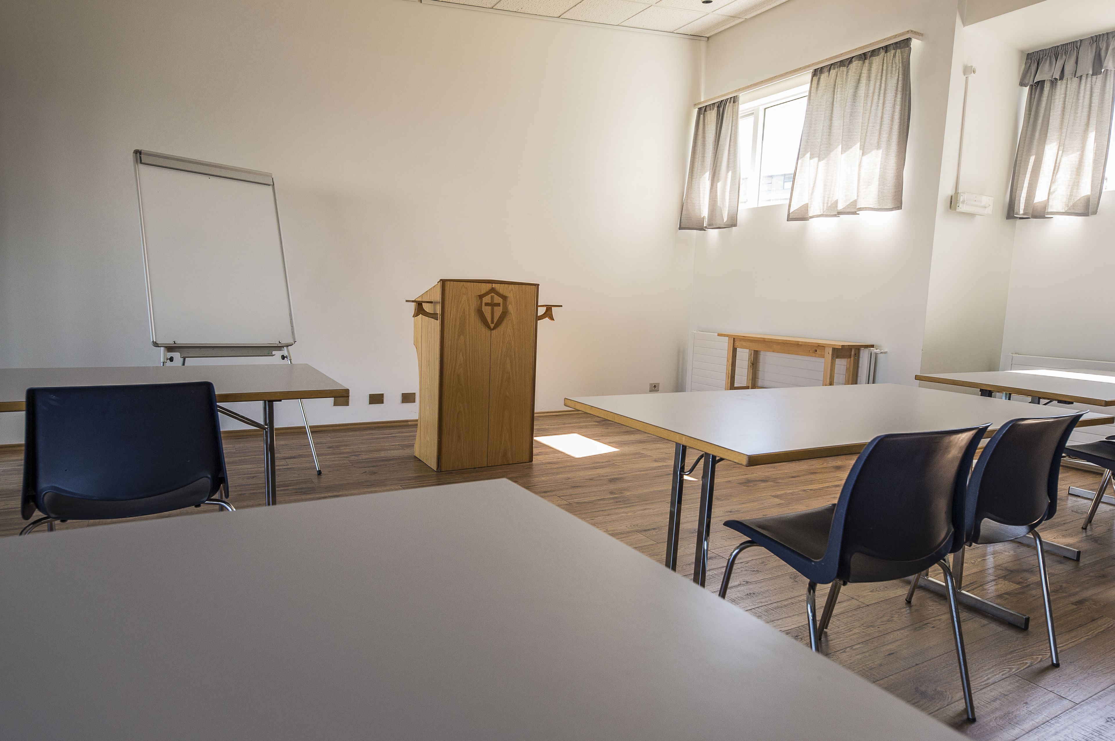 Une salle de conférence équipée d’un tableau blanc, d’un pupitre et de plusieurs chaises.