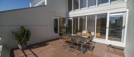 Eine Terrasse mit Tisch und Stühlen, großen Fenstern und einem Blumentopf.