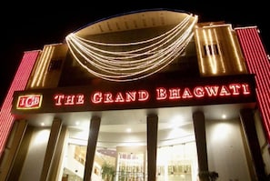 Een hotelentree met een partijtent en een bord met de tekst 'The Grand Bhagwati'.