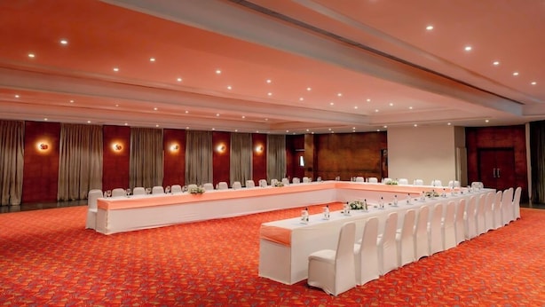 Ein Konferenzraum mit einem langen Tisch, weißen Stühlen und einem roten Teppich.