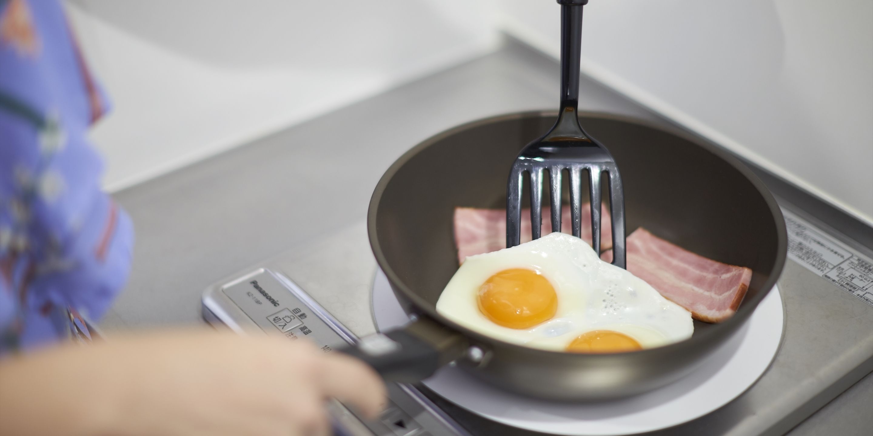 En stekpanna på en spis med två ägg och bitar av bacon.