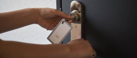 A hand inserting a key into a door lock.