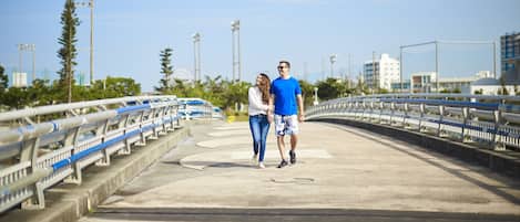 A couple walking on a bridge with railings and a clear sky.