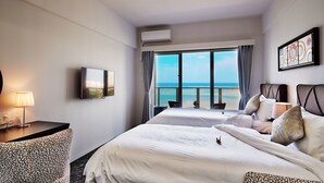 Une chambre d’hôtel avec deux lits, une télévision, un bureau et vue sur l’océan.