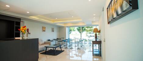 A modern hotel lobby with a reception desk, seating area, and a large window offering a view of the outdoors.