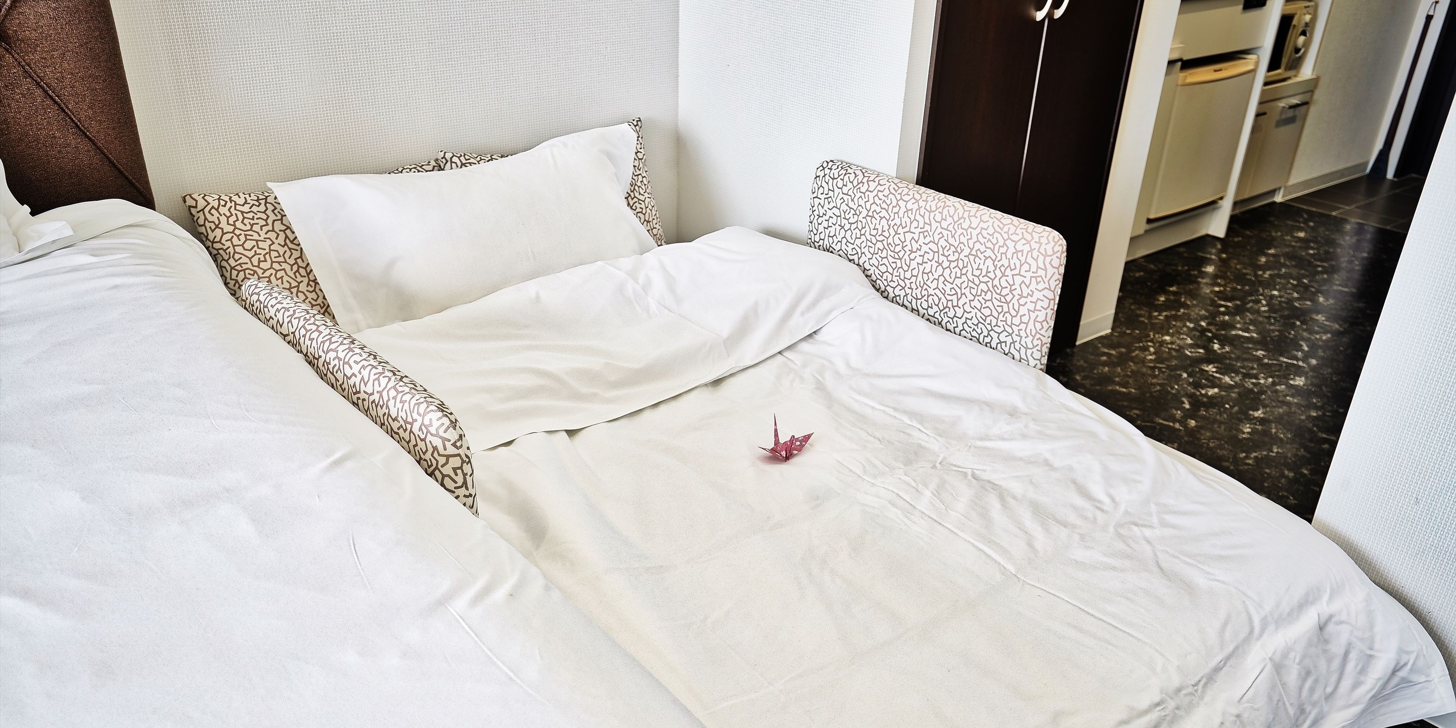 A neatly made bed with patterned pillows and a single decorative item on the bed.