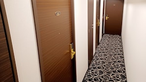 A hotel corridor with wooden doors, a patterned floor, and a clean, modern design. - Akasaka Urban Hotel (Tokyo)