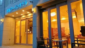A hotel entrance with a glass door, a reception desk, and a seating area with tables and chairs outside. - Akasaka Urban Hotel (Tokyo)