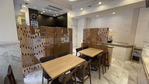 A dining area with a wooden table and chairs, a decorative wall, and a chandelier. - Akasaka Urban Hotel (Tokyo)