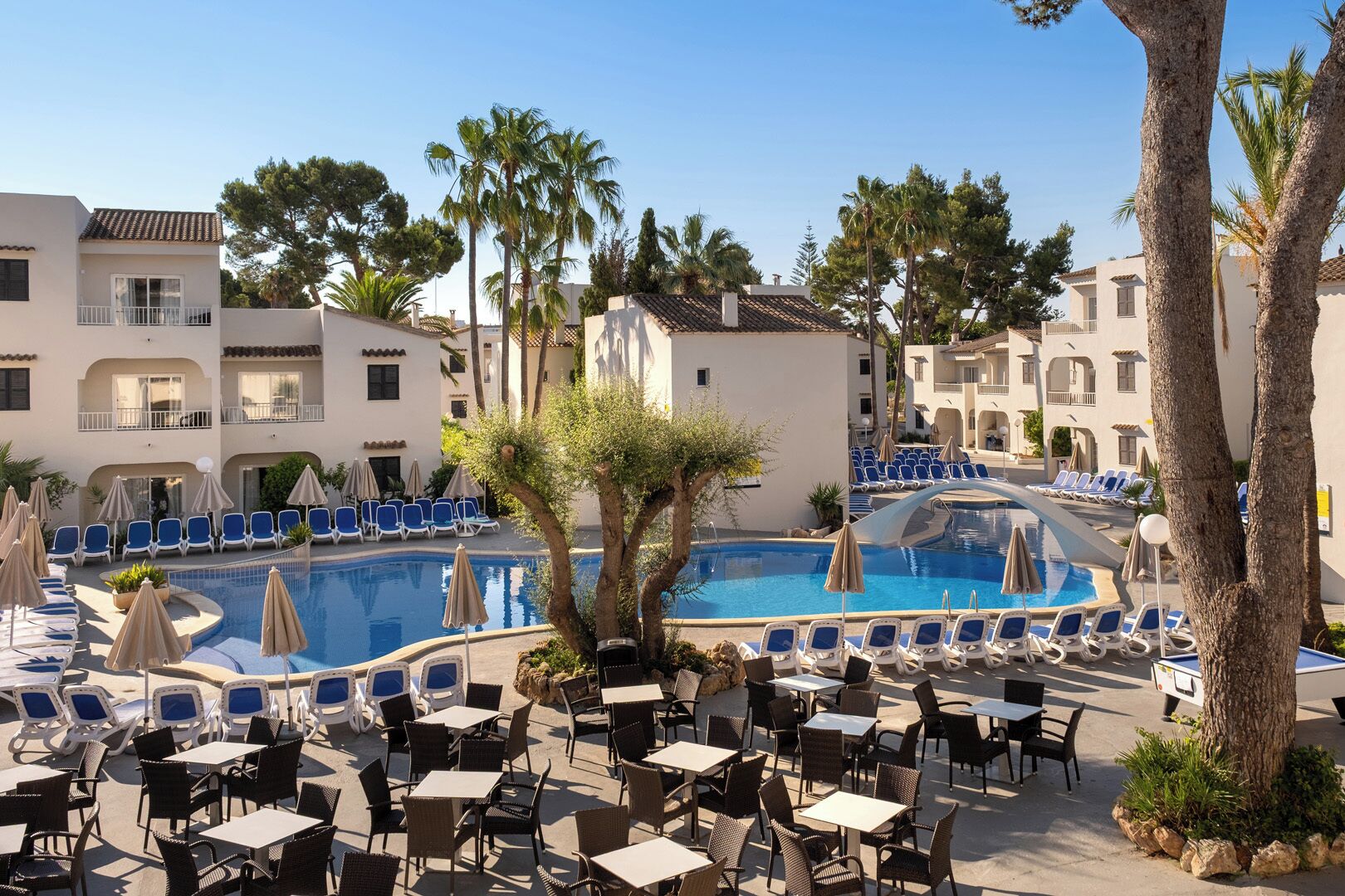 Zona junto a la piscina con sillas de descanso, sombrillas y mobiliario exterior.