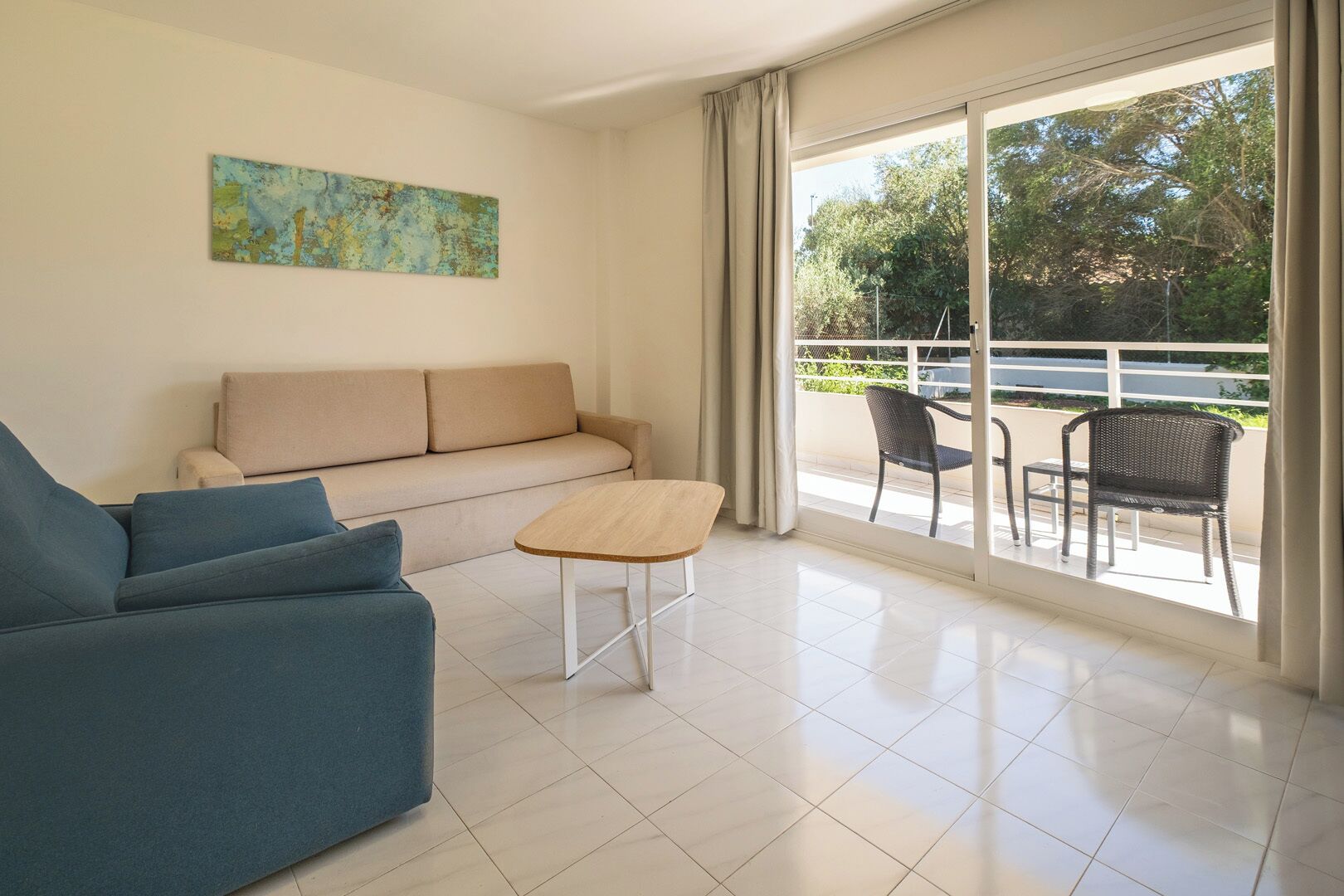 A modern living room with a sofa, a coffee table, and a balcony with chairs.