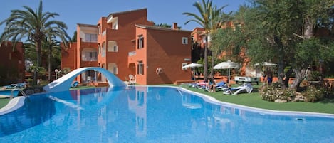 Alberca al aire libre, sombrillas en la alberca y camastros