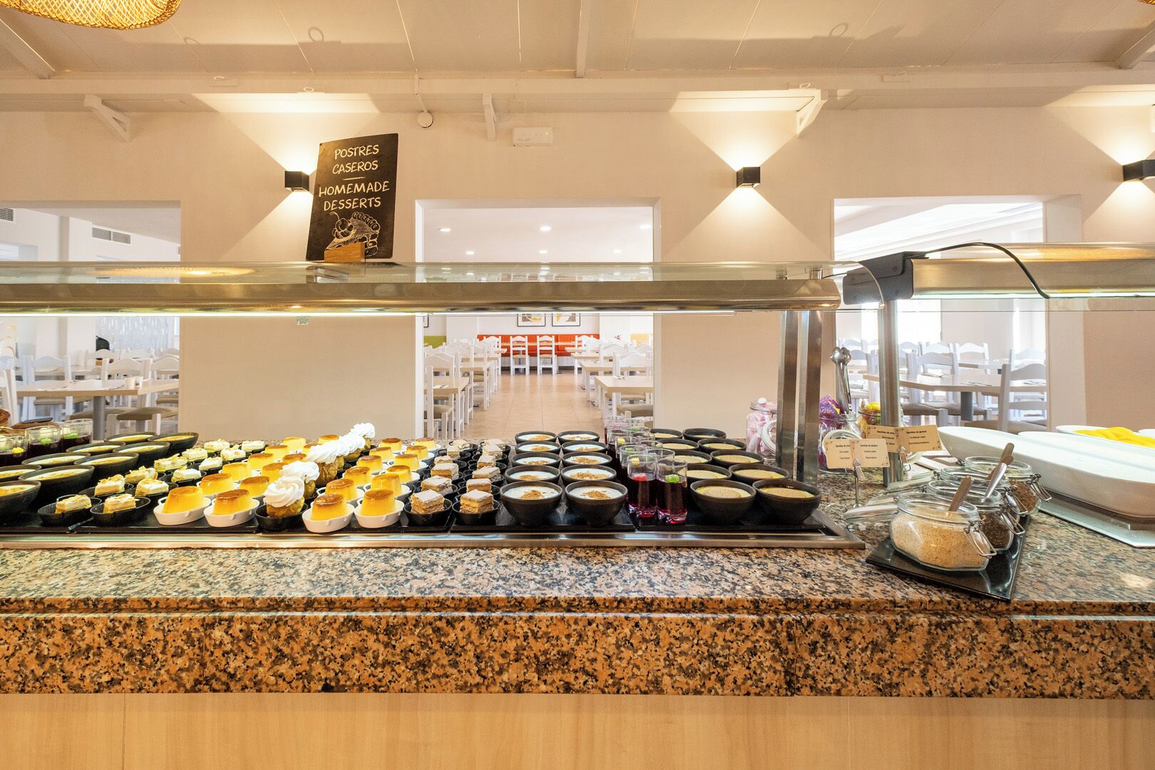 Zona de bufé con diversos postres y alimentos expuestos en una barra.