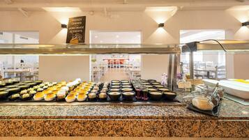 Zona de bufé con diversos postres y alimentos expuestos en una barra.