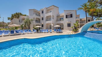 Una piscina al aire libre, sombrillas, tumbonas
