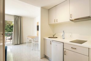 A modern kitchen with white cabinets, a sink, a dishwasher, and a dining area with a table and chairs. - Cabot Club Torre Blanca (Sant Llorenc des Cardassar)