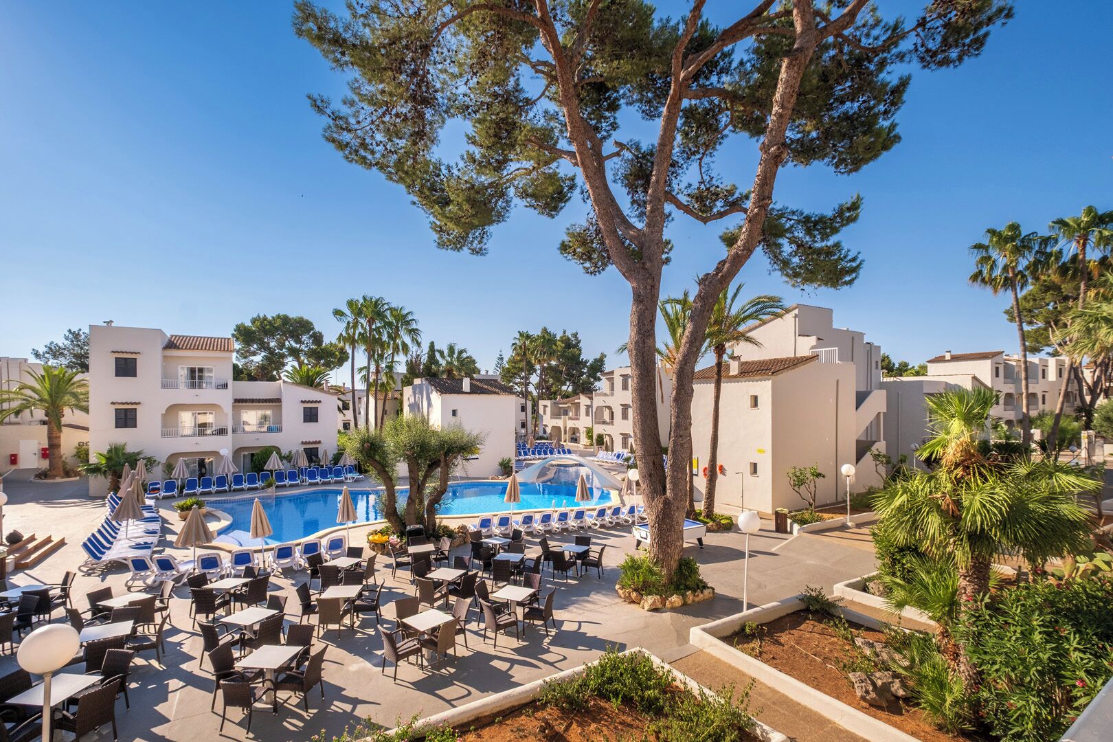 Un resort con piscina, sillones de descanso y mobiliario exterior.