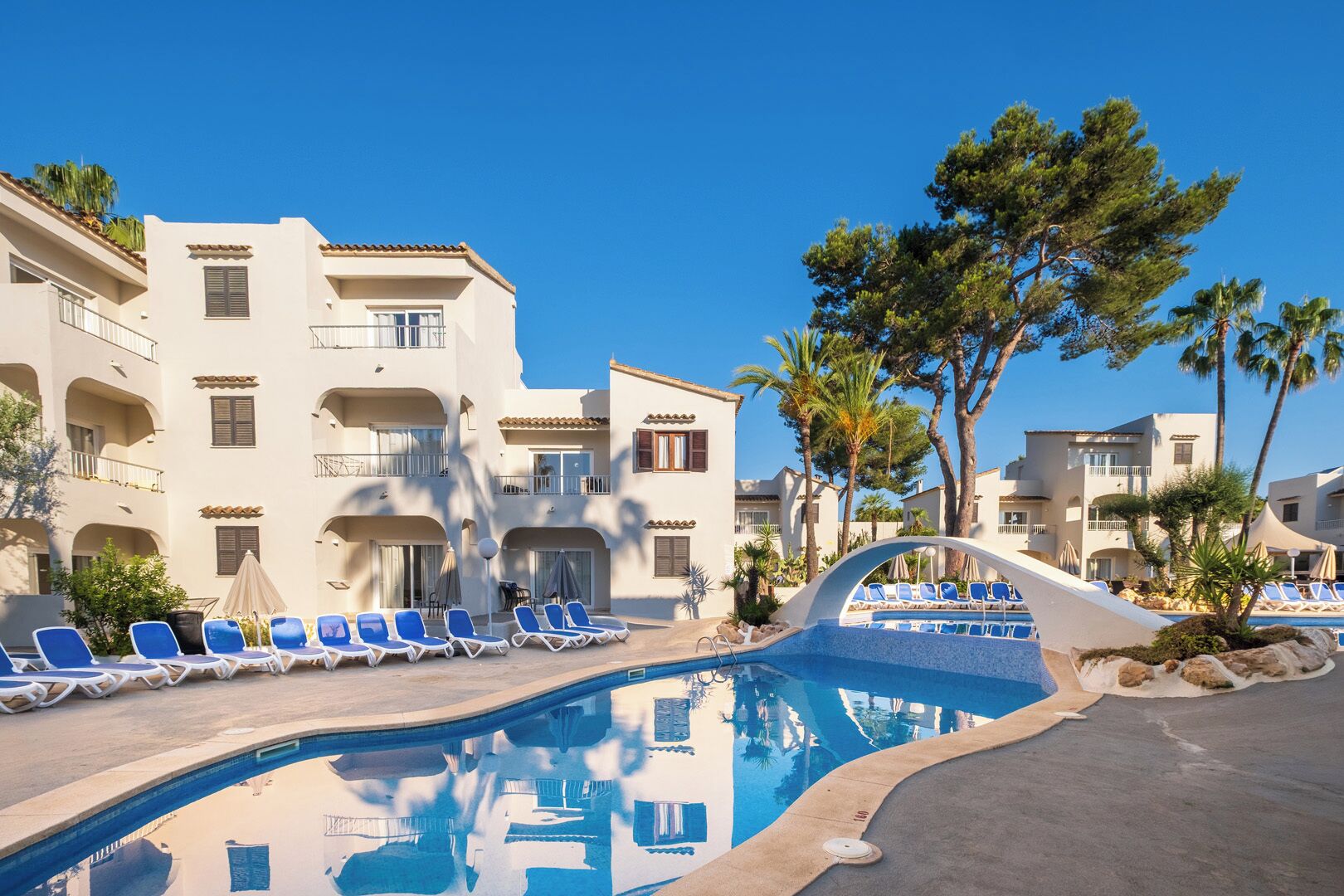 A pool area with lounge chairs and a clear blue sky.