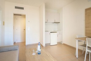 Ett kompakt bostadsutrymme med ett litet kök, en matplats och en soffa.
